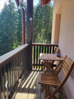 a wooden porch with a wooden table and bench on a balcony at Rogla apartma Rdeča kapica in Vitanje