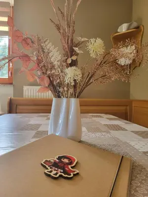 a table with a vase with flowers and a cookie at Rogla apartma Rdeča kapica in Vitanje