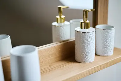 four white and gold bottles on a wooden shelf at Mozirje Comfort Apartments in Mozirje