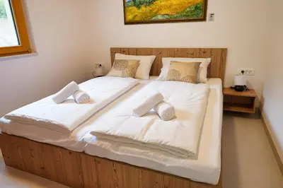 a large bed with white sheets and pillows on it at House Elipsa in Bovec