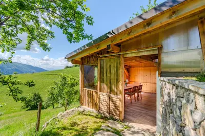 a wooden house with a table on a deck at Holiday Homes Pr Pelaku with Outdoor Sauna in Slappe dʼIdria