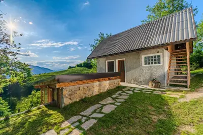 a small cottage with a stone wall and a building at Holiday Homes Pr Pelaku with Outdoor Sauna in Slappe dʼIdria