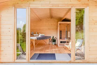 a wooden house with a large glass door at Holiday Homes Pr Pelaku with Outdoor Sauna in Slappe dʼIdria