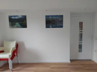 a white room with a chair and two pictures on the wall at Apartment house Petra in Cerklje na Gorenjskem