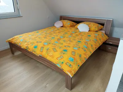a bed with a yellow comforter and pillows on it at Apartment house Petra in Cerklje na Gorenjskem