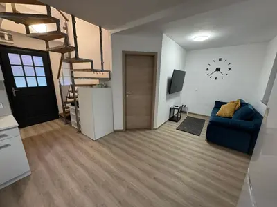 a living room with a blue couch and a spiral staircase at Hiška HOME- TERME ČATEŽ - VKLJUČENE KOPALNE KARTE in Čatež ob Savi