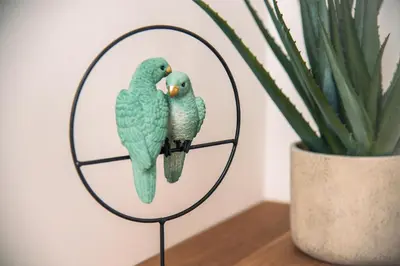 two green parrots on a mirror next to a plant at Apartma Zeleni Biser in Bovec