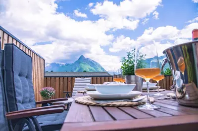 a wooden table with a plate of food and wine glasses at Apartma Zeleni Biser in Bovec