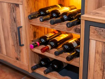 a bunch of wine bottles in a wooden cabinet at Relax apartma Peter in Ptuj