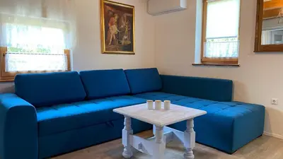 a blue couch in a living room with a table at Goričko view house in Križevci