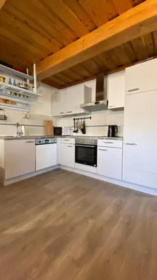 a large kitchen with white cabinets and a wooden ceiling at Goričko view house in Križevci