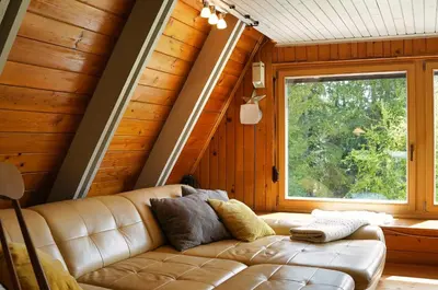 a leather couch in a room with a window at Cottage of peace, Ljubljana area in Rakitna