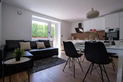 a living room and kitchen with a black couch and chairs at Residence Black&White in Ljubljana