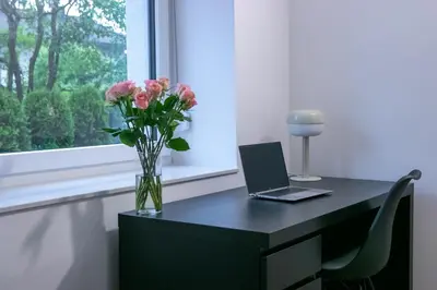 a desk with a vase of flowers and a laptop at Residence Black&White in Ljubljana