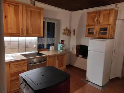 a kitchen with wooden cabinets and a white refrigerator at Holiday home by the emerald river in Soča