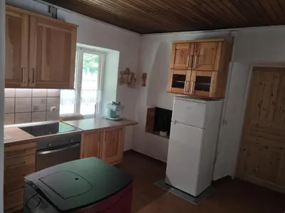 a kitchen with wooden cabinets and a white refrigerator at Holiday home by the emerald river in Soča