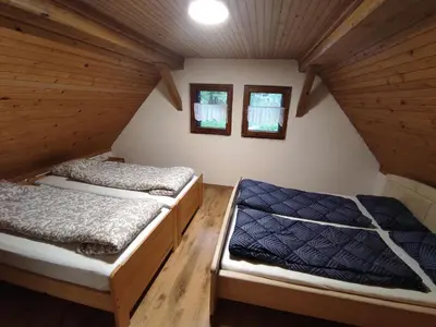 two beds in a attic room with two windows at Holiday home by the emerald river in Soča