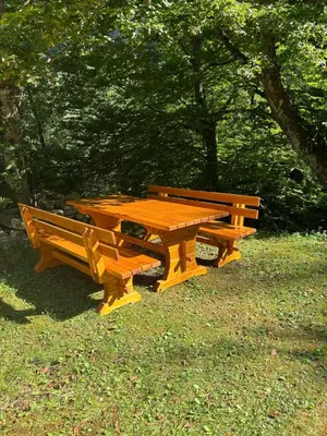 two wooden picnic tables and benches in a park at Holiday home by the emerald river in Soča