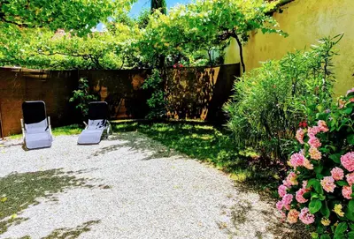 two chairs are sitting in a garden with flowers at Apartma Ježevi in Sežana