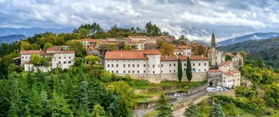 a large white building on a hill with trees at Apartma Ježevi in Sežana