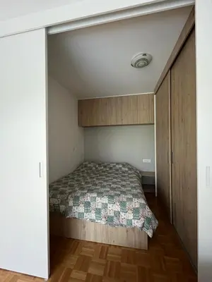 a small bedroom with a bed and a closet at Oasis Atrium Apartment with free parking in Ljubljana