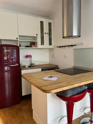a kitchen with white cabinets and a wooden counter top at Oasis Atrium Apartment with free parking in Ljubljana