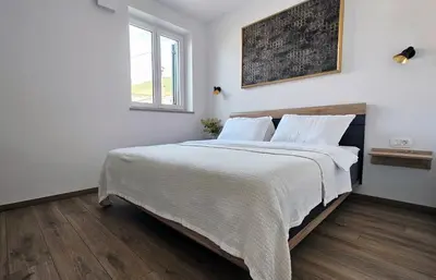 a bedroom with a large bed with white sheets and a window at Apartment MoiRai in Gračišče