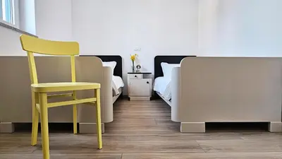 a yellow chair in a bedroom with two beds at Apartment MoiRai in Gračišče