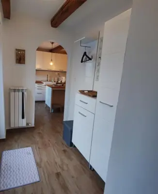 a kitchen with white cabinets and a wooden floor at Casa Rosmarin in Spodnje Škofije