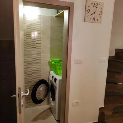 a washing machine in a bathroom with a clock on the wall at Casa Rosmarin in Spodnje Škofije