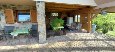 a porch of a house with a green table and chairs at Hiška Tilia in Loče pri Poljčanah