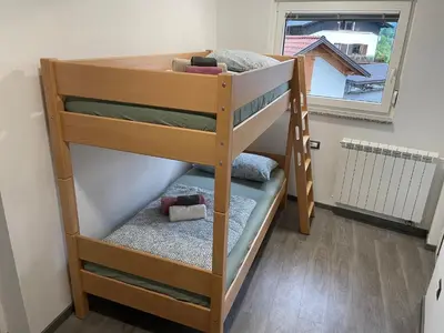 a wooden bunk bed in a room with a window at Apartments Valdi in Tolmin