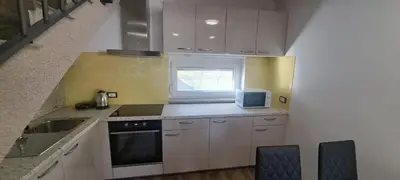 a kitchen with white cabinets and a sink and a window at Apartments Valdi in Tolmin