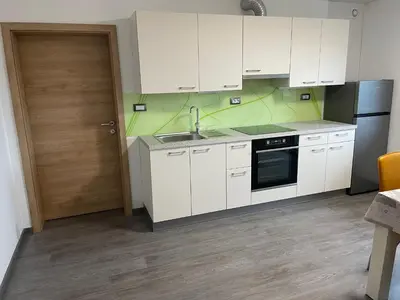 a kitchen with white cabinets and a sink and a door at Apartments Valdi in Tolmin