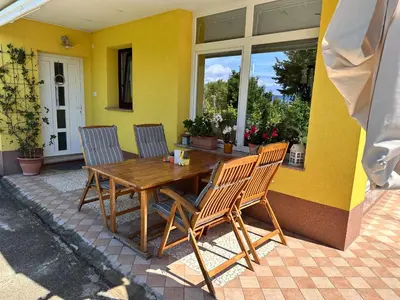a wooden table and chairs on a patio at Apartment HOME SWEET HOME in Zgornje Škofije
