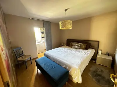 a bedroom with a large bed with a blue stool at Apartment HOME SWEET HOME in Zgornje Škofije