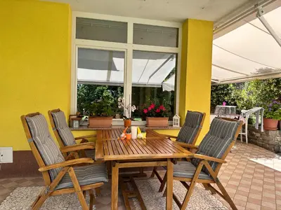 a wooden table and chairs on a patio at Apartment HOME SWEET HOME in Zgornje Škofije