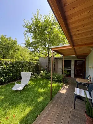 a wooden deck with a table and a bench on the grass at Apartma ART in Kobarid