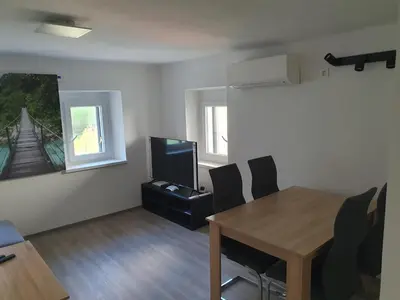 a living room with a dining room table and a television at Apartment Ledince in Most na Soči