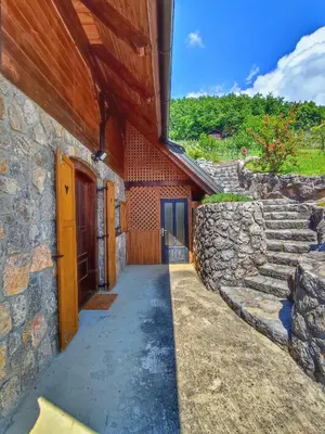 a building with a walkway next to a stone wall at Vineyard cottage Kralj in Uršna Sela