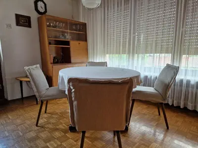 a dining room with a table and chairs and a clock at GreenFamilyAppartment near Ljubljana in Domžale