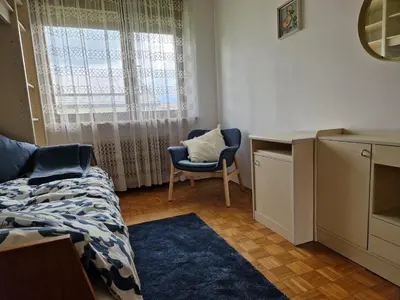 a bedroom with a bed and a chair and a window at GreenFamilyAppartment near Ljubljana in Domžale
