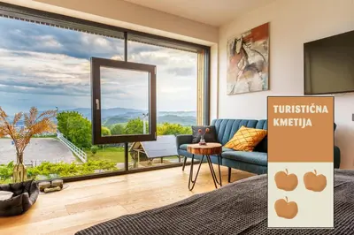 a living room with a blue couch and a large window at Tourist Farm HOTEL FROST in Maribor