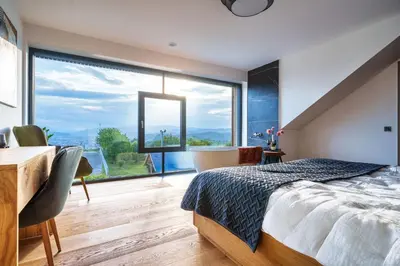 a bedroom with a large window and a bed and a desk at Tourist Farm HOTEL FROST in Maribor