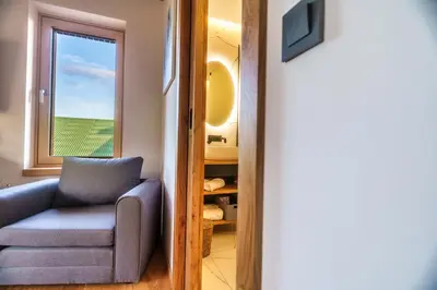 a living room with a chair and a window at Tourist Farm HOTEL FROST in Maribor
