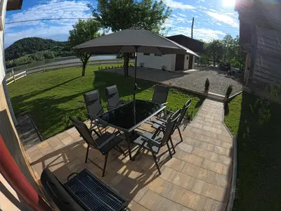 a patio with a table and chairs under an umbrella at Slivnisko Jezero Hisa in Veliki Rakitovec