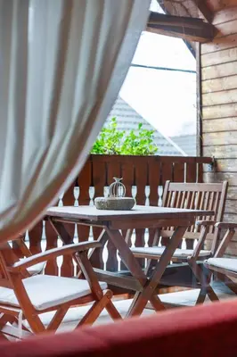 a wooden table and chairs on a porch at Hiša na Dovjem in Mojstrana