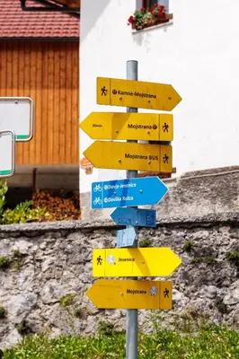 a street sign with many signs on a pole at Hiša na Dovjem in Mojstrana