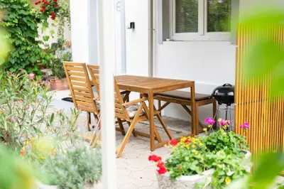 a wooden table and chairs on a porch with flowers at Studio Maria with Free Parking in Bohinj