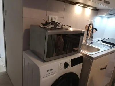 a microwave on top of a washing machine in a kitchen at apartma Lesnik Vila Ziba in Bohinj